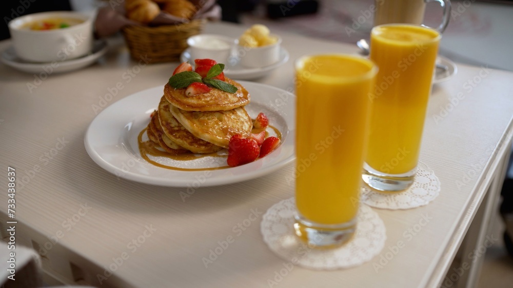 The chef pours jam on pancakes for breakfast in a hotel room. Fritters for breakfast with jam. Delicious oatmeal pancakes with jam. Pancakes covered with jam. The chef pours jam on pancakes for breakfast in a hotel room. Fritters for breakfast with jam. Delicious oatmeal pancakes with jam. Pancakes covered with jam.