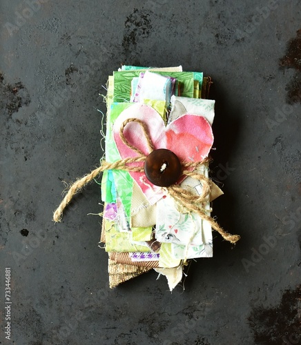 Sewing supplies bundle of fabric scraps with heart brown button jute on a dark background