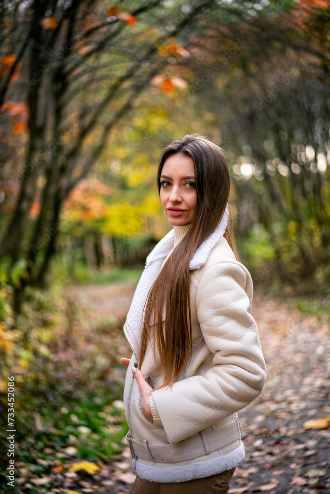 Beautiful young woman in white coat walks in the autumn park Beautiful young woman in white coat walks in the autumn park