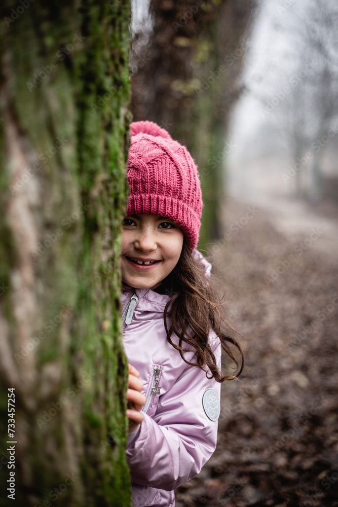 waist up portrait of happy girl hiding behind the tree on a foggy day waist up portrait of happy girl hiding behind the tree on a foggy day