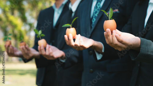 Group of business people holding repuposed eggshell transformed into fertilizer pot, symbolizing commitment to nurture and grow sprout or baby plant as part of a corporate reforestation project. Gyre © Summit Art Creations