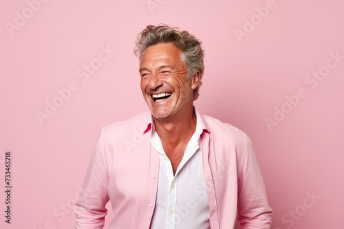 Portrait of happy senior man laughing and looking at camera isolated over pink background