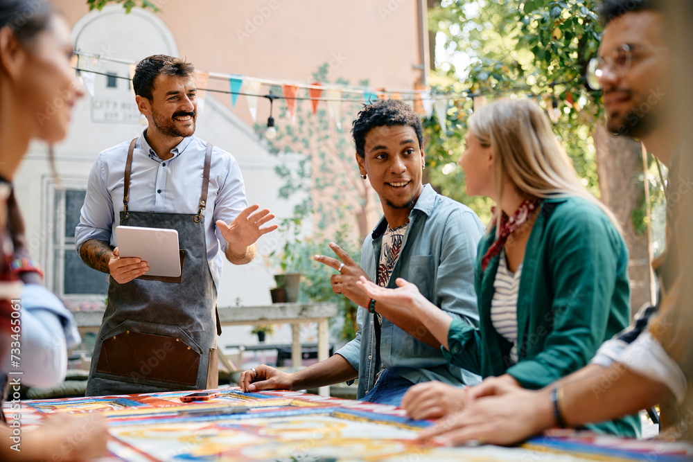 Multiracial group of happy friends talking to waiter in cafe. Multiracial group of happy friends talking to waiter in cafe.
