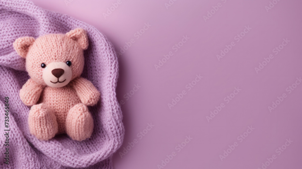 Fototapeta premium A small knitted amigurumi bear toy on a violet blanket, on a violet background. Flat lay, top view, copy space. space for text