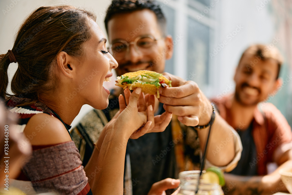 Happy couple sharing taco while eating in Mexican restaurant.. - obrazy, fototapety, plakaty 