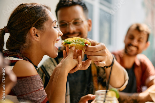 Happy couple sharing taco while eating in Mexican restaurant..