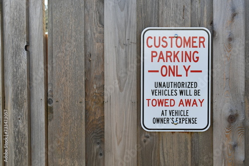 Customer Parking Only sign on wooden fence.