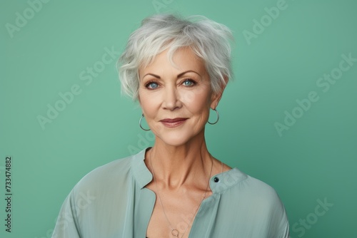 Portrait of smiling senior woman with grey hair, isolated on green background