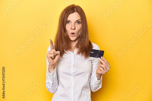 Redhead holding credit card, financial concept having some great idea, concept of creativity.