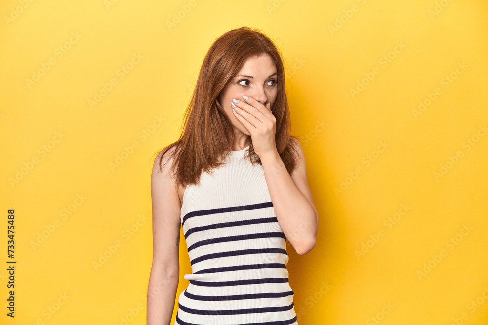 Redhead in a tank top, casual studio shot thoughtful looking to a copy space covering mouth with hand. Redhead in a tank top, casual studio shot thoughtful looking to a copy space covering mouth with hand.