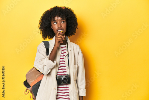 Teen girl with backpack, camera, ready for vacation relaxed thinking about something looking at a copy space.