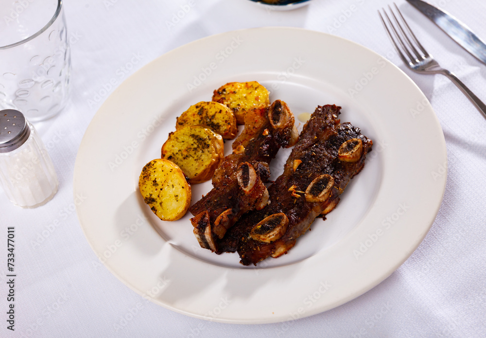 Beef rib steak, churrasco de ternera with fried potatoes, served on table.