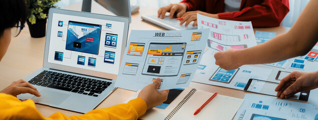 Panorama banner of startup UX developer or company employee design user interface or UI prototype for mobile application or website software with software display on laptop monitor in office. Synergic