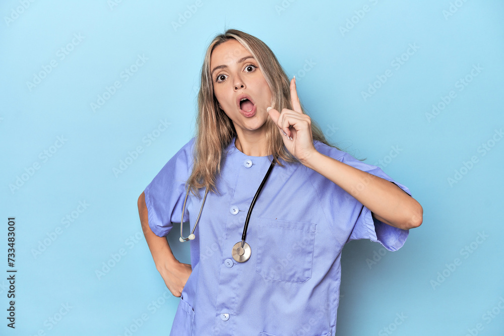 Young caucasian nurse in blue studio having an idea, inspiration concept. Young caucasian nurse in blue studio having an idea, inspiration concept.