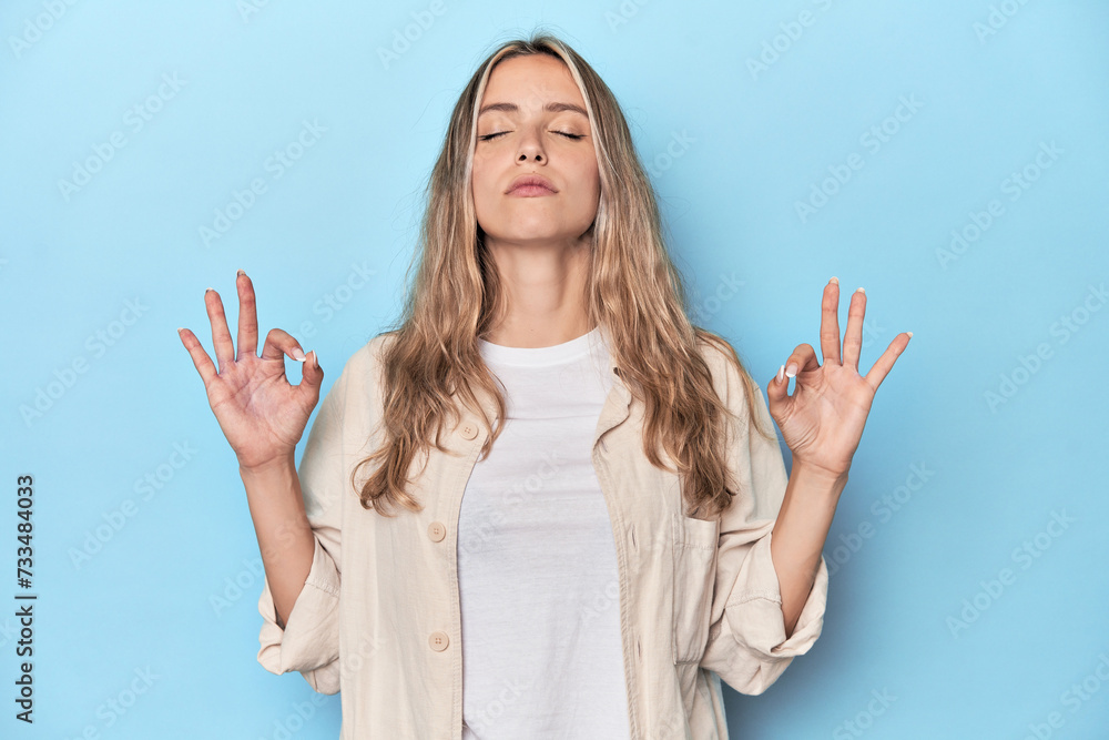 Blonde young caucasian woman in blue studio relaxes after hard working day, she is performing yoga. Blonde young caucasian woman in blue studio relaxes after hard working day, she is performing yoga.