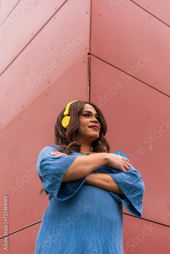 Trans woman listening to music. Red background. Proud expression. photo