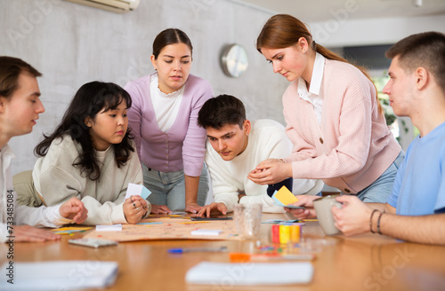 Happy girls and boys play board games in classroom