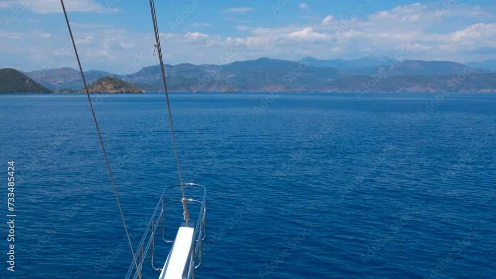 Front side of yacht in turquoise sea. A view of front side on luxury boat against blue hills in the open sunny sea. Front side of yacht in turquoise sea. A view of front side on luxury boat against blue hills in the open sunny sea.