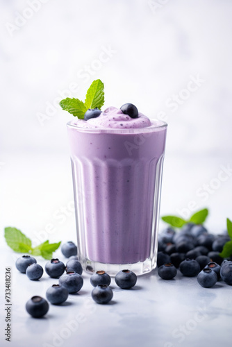Blueberry smoothie in tall glass in white modern kitchen with fresh blueberries and mint leaves