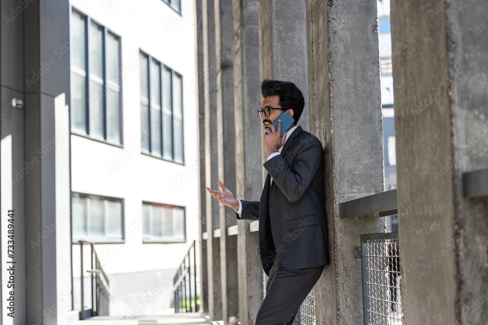Stylish young businessman in office area with a phone in hands Stylish young businessman in office area with a phone in hands