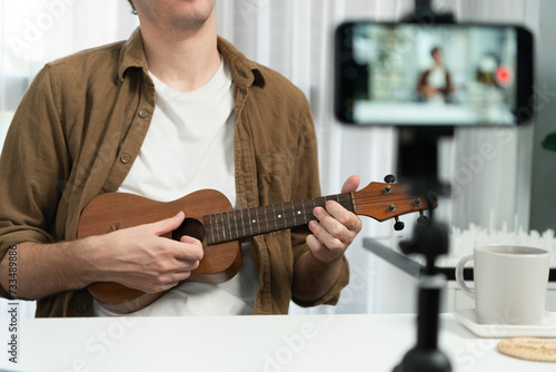 Host channel of influencer singing with playing guitar in broadcast modern home studio to fanclub. Time slot of music blogger showing on live social media online on cellphone in audio creator. Gusher. photo