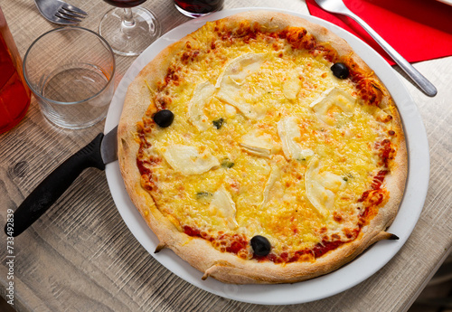 Delicious traditional Italian cheese pizza with tomato sauce and olives served at restaurant