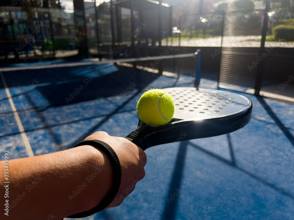 Pala de pádel con una pelota para jugar el deporte de mayor crecimiento en los últimos años a nivel mundial. Cancha de pádel en verano, el momento perfecto para practicar esta disciplina deportiva.