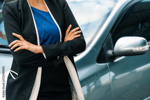 Confident professional business woman standing beside the car. Concept of car rental business and sales occupation. uds