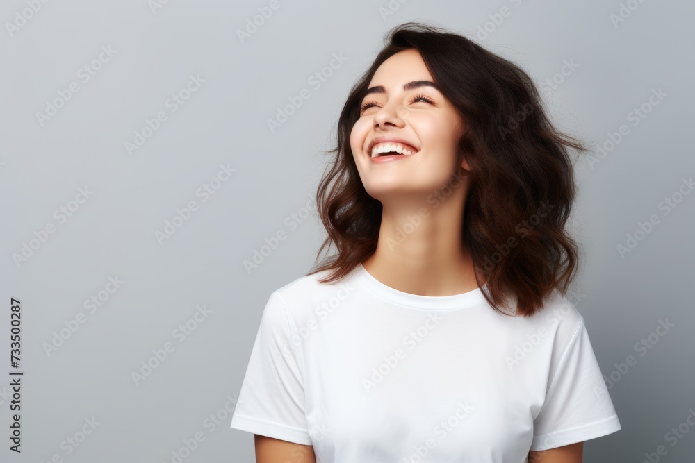 Portrait of happy smiling young woman in white t-shirt on grey background Portrait of happy smiling young woman in white t-shirt on grey background
