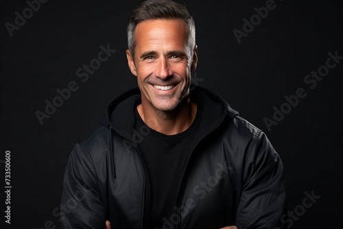 Portrait of a handsome middle-aged man smiling over black background.