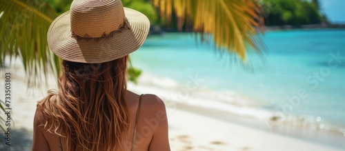Stylish Woman Embracing the Tropical Vibe with her Beach Hat at the Beautiful Woman, Tropical Beach, Wearing a Hat photo