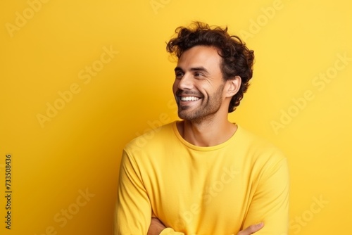Portrait of handsome young man in yellow sweater smiling over yellow background © Iigo