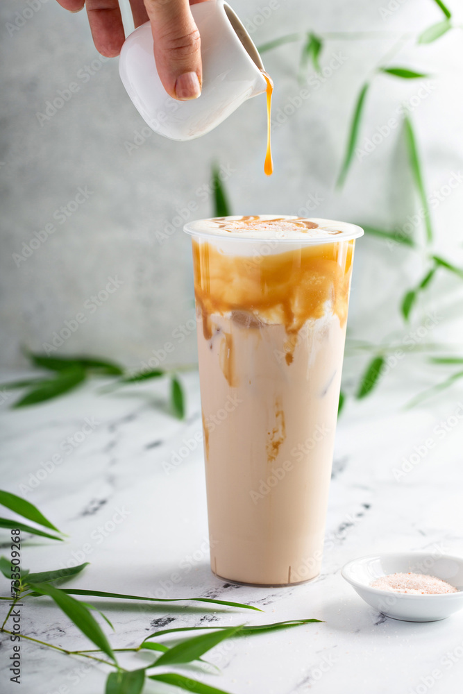 Caramel milk tea latte in a tall glass with cold foam and caramel sauce Caramel milk tea latte in a tall glass with cold foam and caramel sauce
