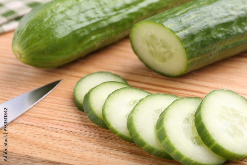 Fresh cucumbers and knife on wooden cutting board, closeup Fresh cucumbers and knife on wooden cutting board, closeup