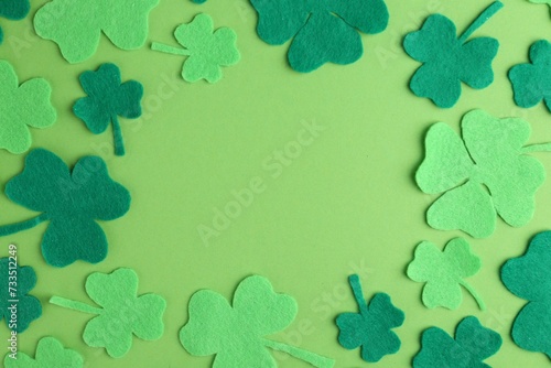 St. Patrick's day. Frame of decorative clover leaves on green background, flat lay. Space for text