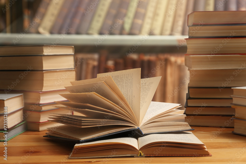 Fototapeta premium Different books on wooden table in library
