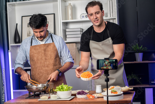 Healthy food in kitchen with chef influencers presenting fresh salad roll on cooking show streaming via smartphone on social media live, preparing ingredients vegetable soft tortilla wrap. Sellable.