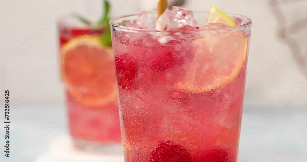 Raspberry lemonade or cocktail with slices of lemon and fresh mint being stirred with a straw Raspberry lemonade or cocktail with slices of lemon and fresh mint being stirred with a straw