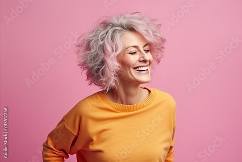 Portrait of happy mature woman laughing and looking up against pink background