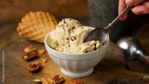 Butter pecan ice cream with candied pecan pieces being eaten with a spoon photo