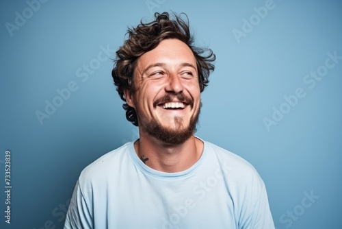 Portrait of a funny young man laughing on a blue background. © Iigo