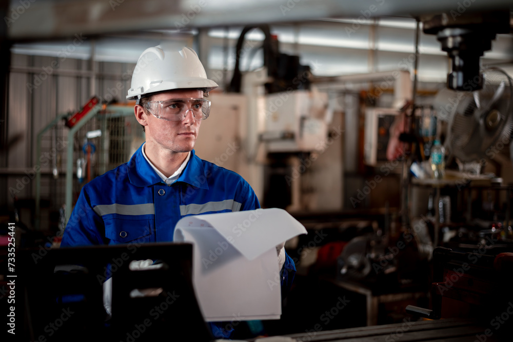 Industry engineer wearing safety uniform control operating lathe grinding machine working with detail document on hand in industry factory is metal manufacture industry concept. Industry engineer wearing safety uniform control operating lathe grinding machine working with detail document on hand in industry factory is metal manufacture industry concept.
