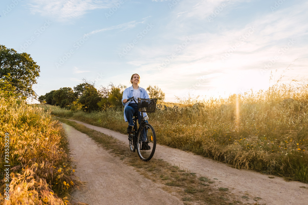 beauty young blonde woman cycling in a field at sunset