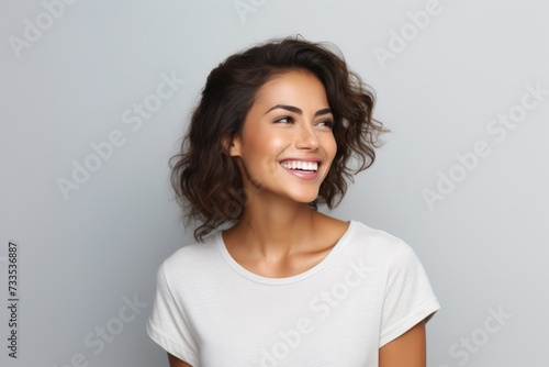 Portrait of happy smiling beautiful young woman in blank white t-shirt, over grey background