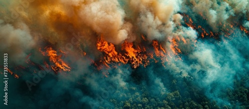 Bird's-eye view of a forest fire or wildfire captured by an aerial drone, showing dense smoke clouds and the combustion of parched vegetation.