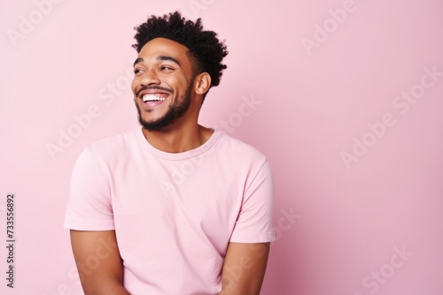 Portrait of a happy young african american man smiling against pink background photo