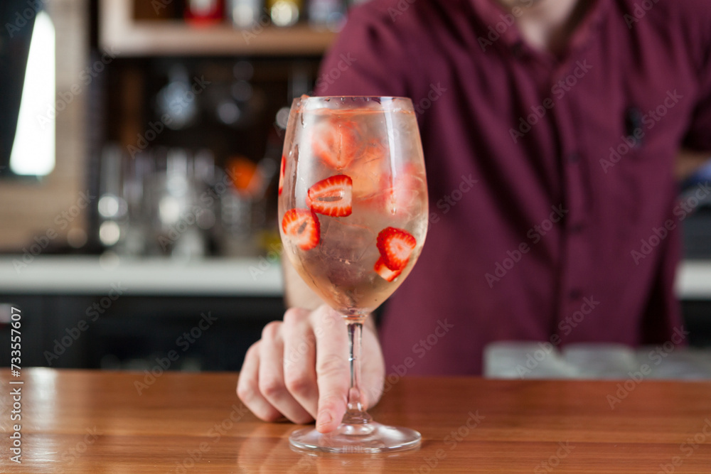 Bartender making a fruity summer cocktail at a bar. 
