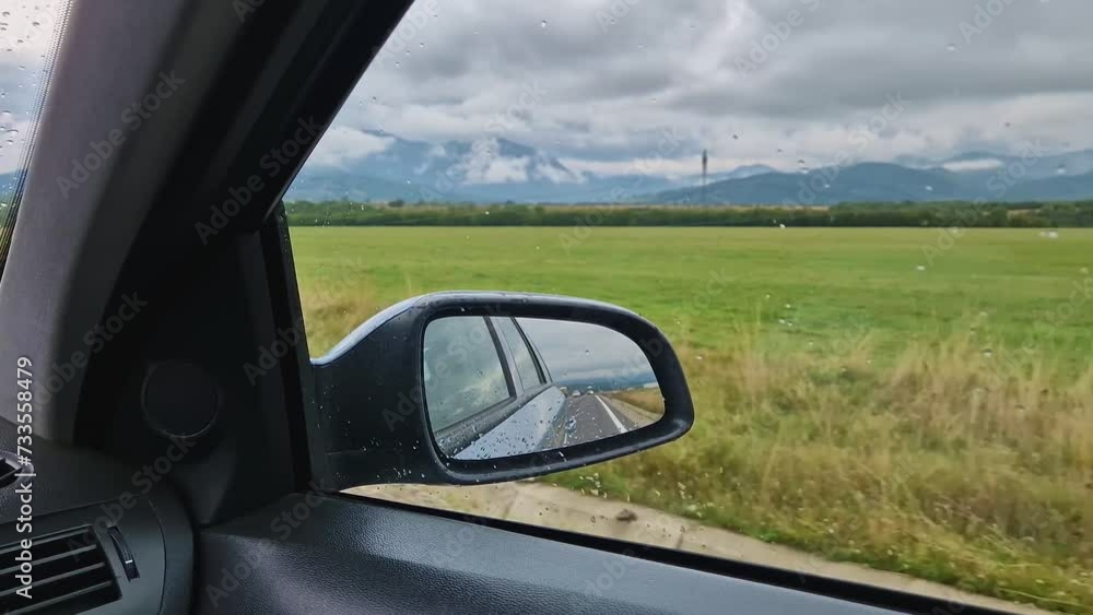 Car moving on the highway with mountains scene out of the window. The view to the side mirror Car moving on the highway with mountains scene out of the window. The view to the side mirror