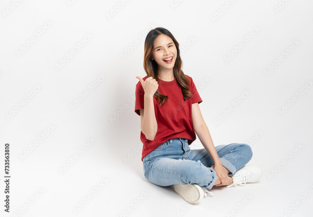 Happy smiling young woman sitting and shows hand pointing to the top, isolated on white background. Happy smiling young woman sitting and shows hand pointing to the top, isolated on white background.