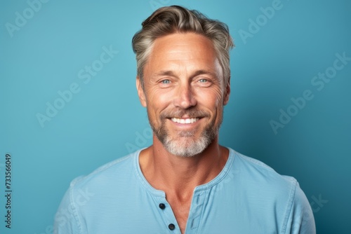 Portrait of a handsome mature man smiling at the camera against blue background